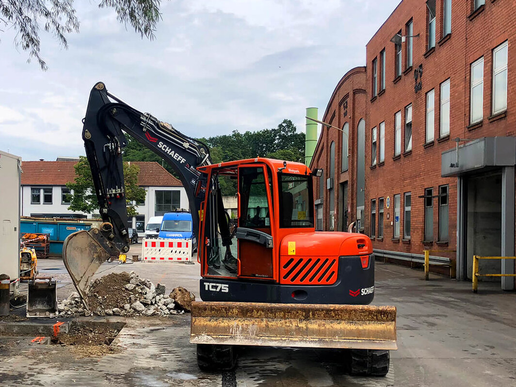 Bagger im Einsatz zur Öffnung einer Asphaltdecke